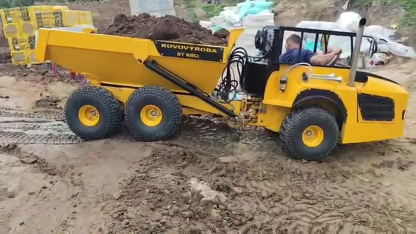 Žlutý kloubový dumper KOVOVÝROBA BY KRCI naložený zeminou, boční pohled s řidičem