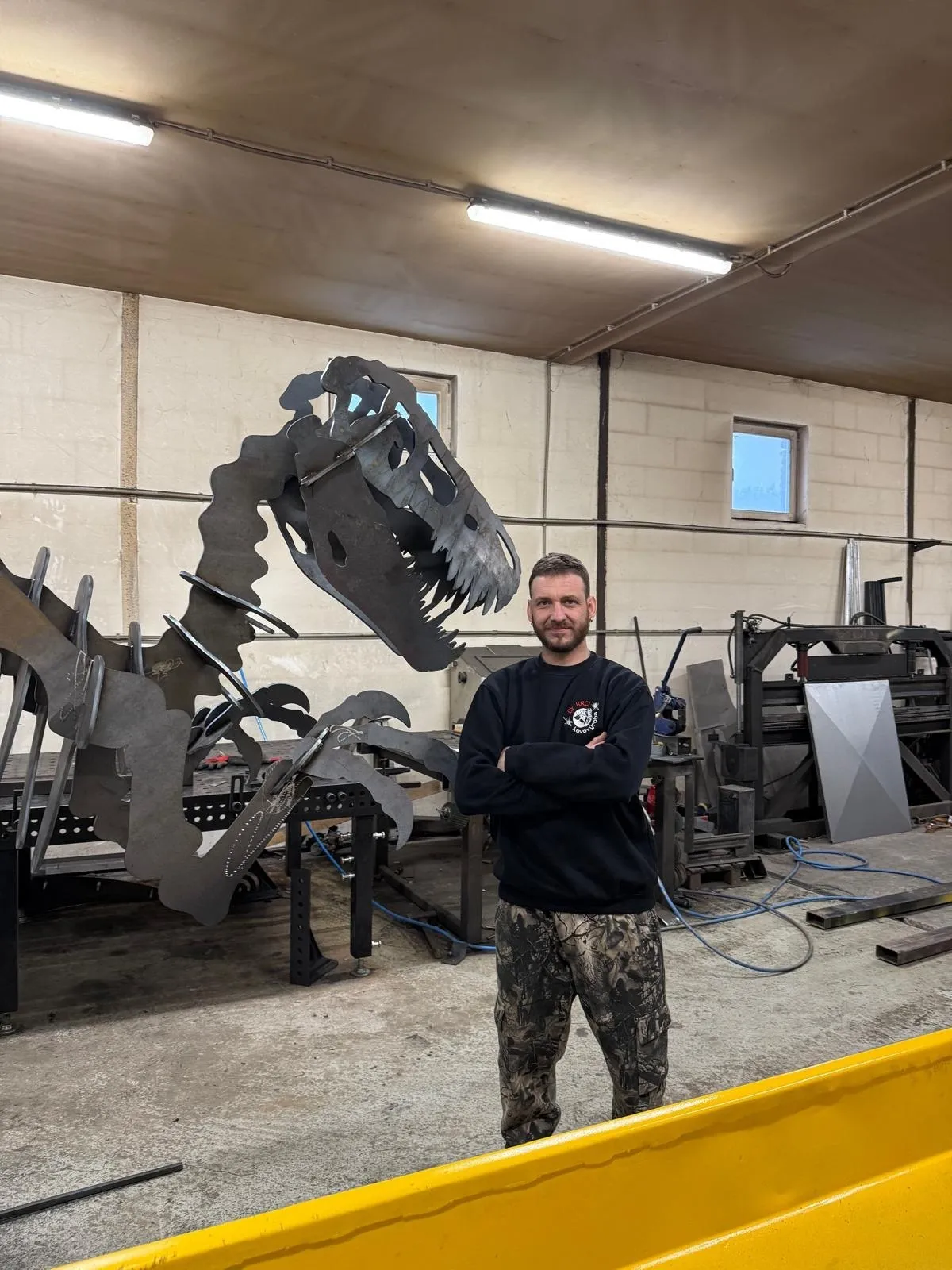 Jan Krtek v dílně u kovové sochy dinosaura